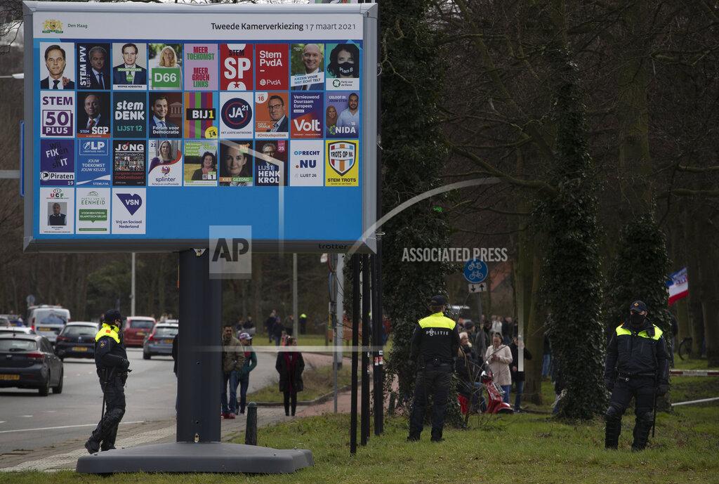 Peter Dejong Police block the access for demonstrators next to an election billboard during a rally, ahead of three days of voting starting Monday in a general election, to protest government policies including the curfew, lockdown and coronavirus related restrictions in The Hague, Netherlands, Sunday, March 14, 2021. (AP Photo/Peter Dejong)