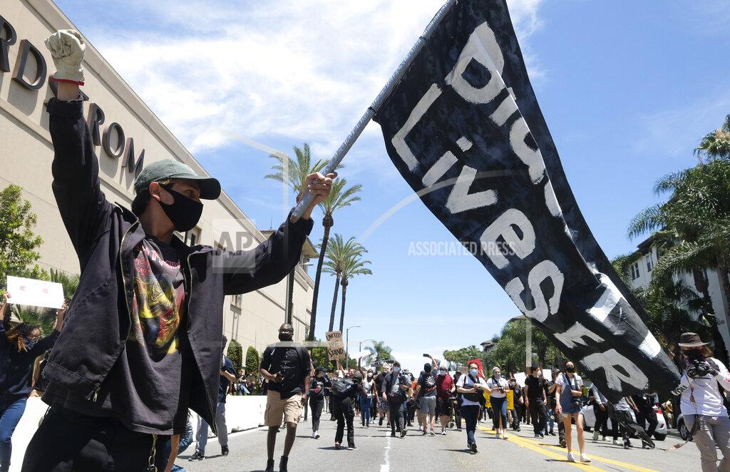 Ringo H.w. Chiu A man holds a flag during a protest over the death of George Floyd in Los Angeles, Saturday, May 30, 2020. Protests across the country have escalated over the death of George Floyd who died after being restrained by Minneapolis police officers on Memorial Day, May 25.(AP Photo/Ringo H.W. Chiu)