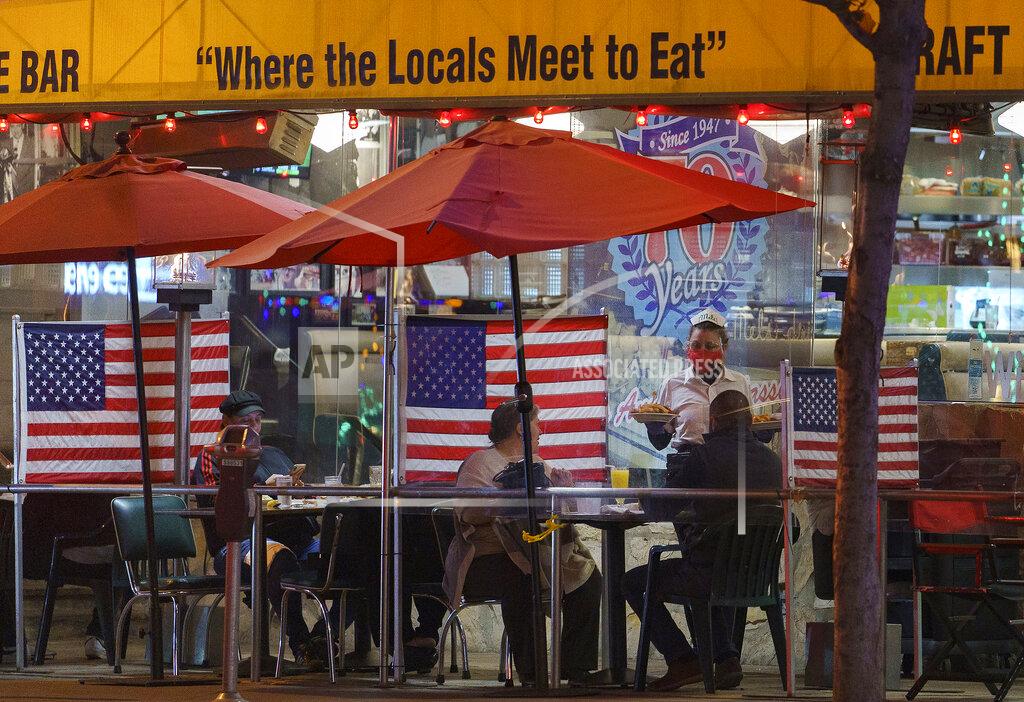 Damian Dovarganes FILE - In this Nov. 24, 2020, file photo, patrons sit outdoors for dinner separated by plastic dividers with national flags at Mel's drive-in restaurant, in West Hollywood, Calif. Los Angeles County can reopen even more businesses while expanding how many people are allowed to dine indoors or catch a movie, California public health officials announced Tuesday, March 30, 2021. The county of 10 million people was one of several that moved into the state's orange tier, which is the second-least restrictive of California's four-tier system. (AP Photo/Damian Dovarganes, File)