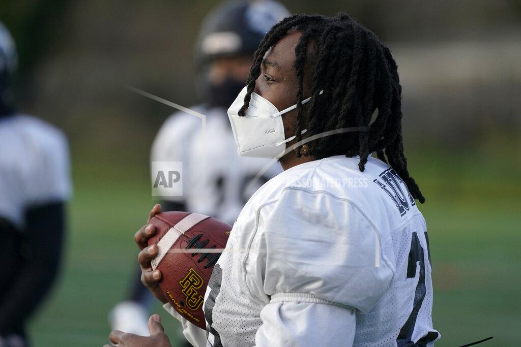 Ted S. Warren Malik White, a senior running back at Pacific Lutheran, wears a KN95 mask as he holds a football during practice Tuesday, Feb. 2, 2021, on campus in Tacoma, Wash. For all the attention heaped on the FBS level of college football last fall as it tried to play, it will not be the only college football during the 2020-21 sports calendar as a handful of NCAA Division III and NAIA programs begin some form of a winter/spring season Saturday, Feb. 6. (AP Photo/Ted S. Warren)