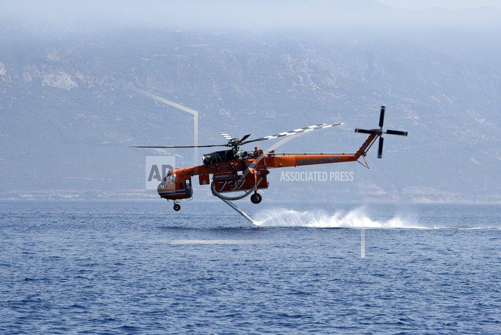 Andreas Alexopoulos A helicopter fills up with water from the sea near Lampiri village, east of Patras city, Greece, Sunday, Aug. 1, 2021. A wildfire that broke out Saturday in western Greece forced the evacuation of four villages and people on a beach by the Fire Service, the Coast Guard and private boats, authorities said. (AP Photo/Andreas Alexopoulos)