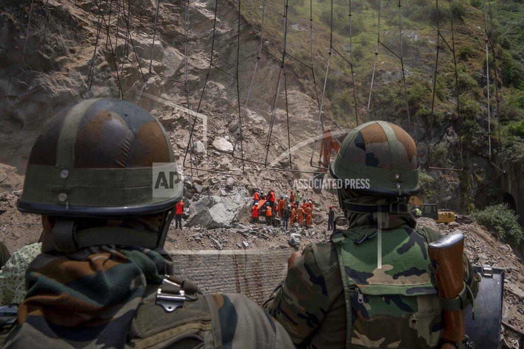 Dar Yasin Indian army soldiers watch from a distance as earth movers dig through the rubble of a collapsed tunnel in Ramban district, south of Srinagar, Indian controlled Kashmir, Friday, May 20, 2022. An official in Indian-controlled Kashmir said Friday that 10 workers were trapped after part of a road tunnel collapsed in the Himalayan region. (AP Photo/Dar Yasin)