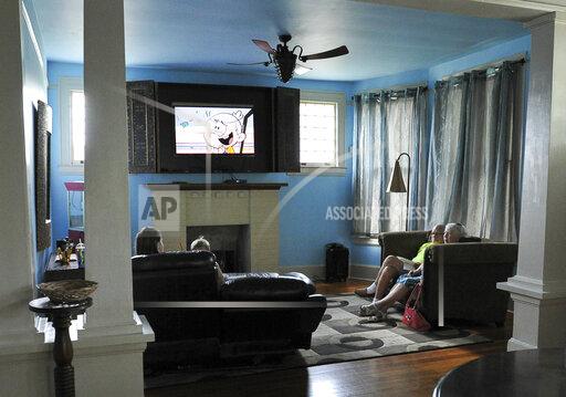 Family members gather in the living room of a local Airbnb property on Aug. 26, 2017, in Brownsville, Texas. Thousands of Airbnb hosts have agreed to house refugees as part of the online lodging marketplace’s philanthropic program to provide emergency temporary housing to those who need it. It’s a program so successful it is seen as a model for those working to resettle refugees and has become a core mission of Airbnb.org, the nonprofit that celebrates its first anniversary Tuesday, Dec. 7, 2021. Airbnb's philanthropy started in 2012 after Hurricane Sandy and continued for years, including Hurricane Harvey in 2017 before it expanded its scope. (Jason Hoekema/The Brownsville Herald via AP)