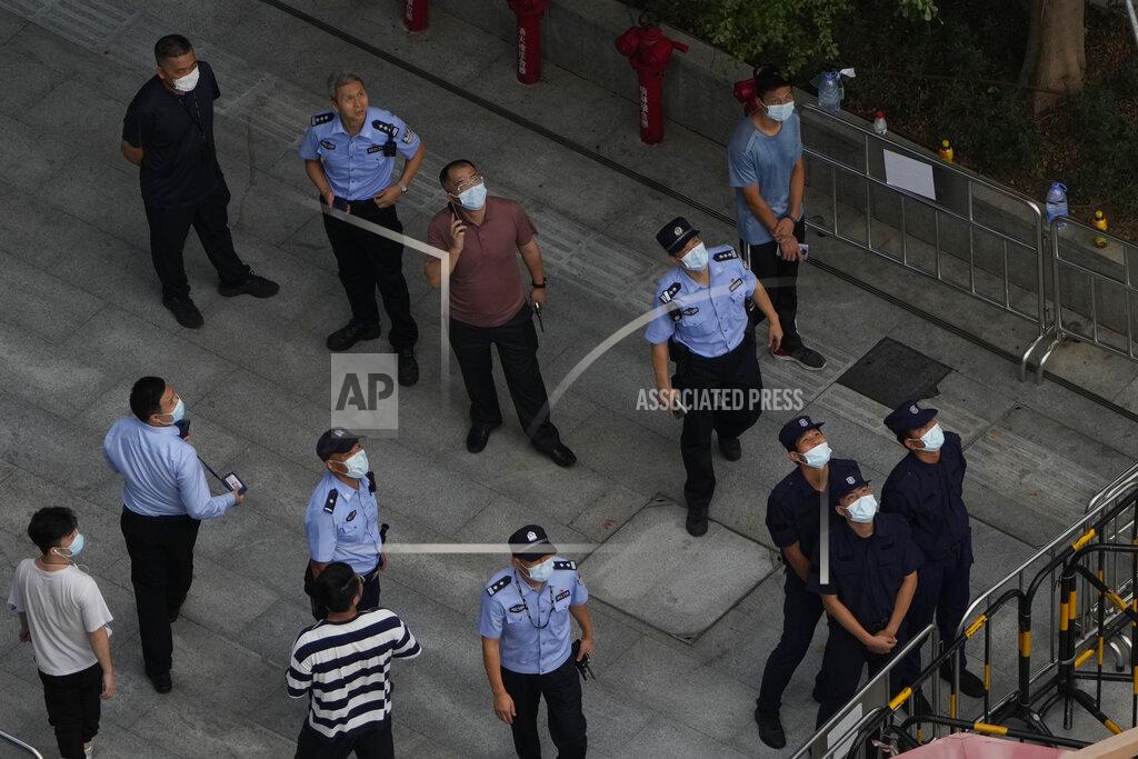 Ng Han Guan Police officers and security personnel react to something in the sky near the headquarters of the real estate developer Evergrande Group, Thursday, Sept. 23, 2021, in Shenzhen, southern China. Fears that the developer's possible default on multibillion-dollar debts might send shockwaves through global financial markets appeared to ease Thursday as creditors waited to see how much they might recover. (AP Photo/Ng Han Guan)