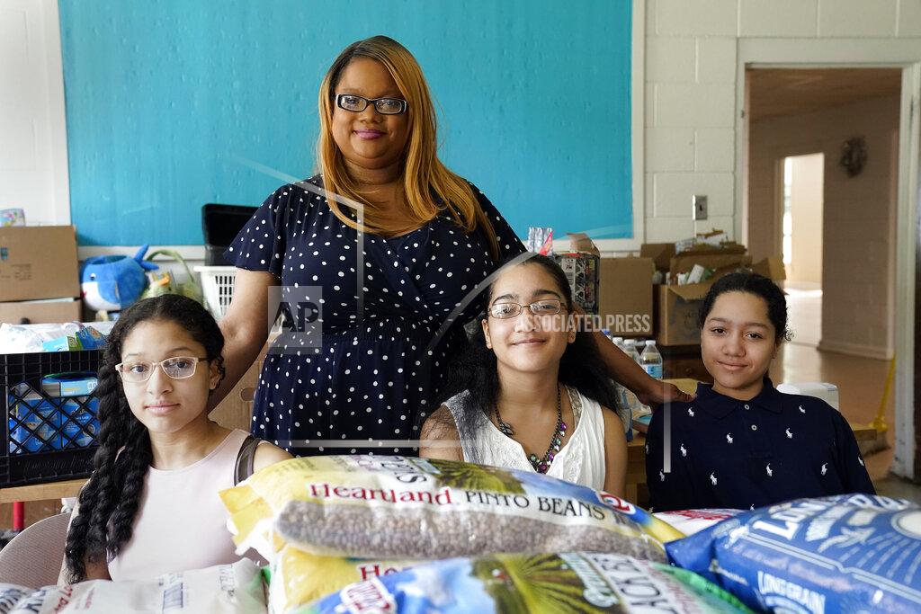 Gerry Broome Aja Purnell-Mitchell stands next to her three children, Kyla, 13, left; Kyra, 15, and Cartier, 14, at a local food hub in Durham, N.C., on Friday, May 28, 2021, where they often help their mother. The teenagers have been learning remotely since last March but now plan to attend summer school after being vaccinated. (AP Photo/Gerry Broome)