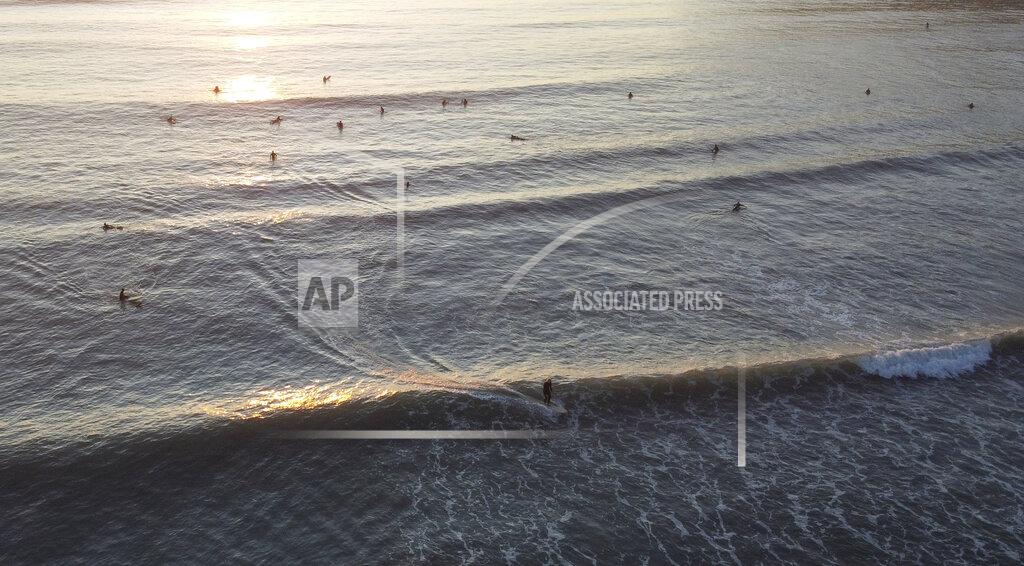 Mark Baker Surfers enjoy a sunrise surf as level four restrictions are eased in Christchurch, New Zealand, Tuesday, April 28, 2020. New Zealand eased its strict lockdown restrictions to level three at midnight to open up certain sections of the economy but social distancing rules will still apply. (AP Photo/Mark Baker)
