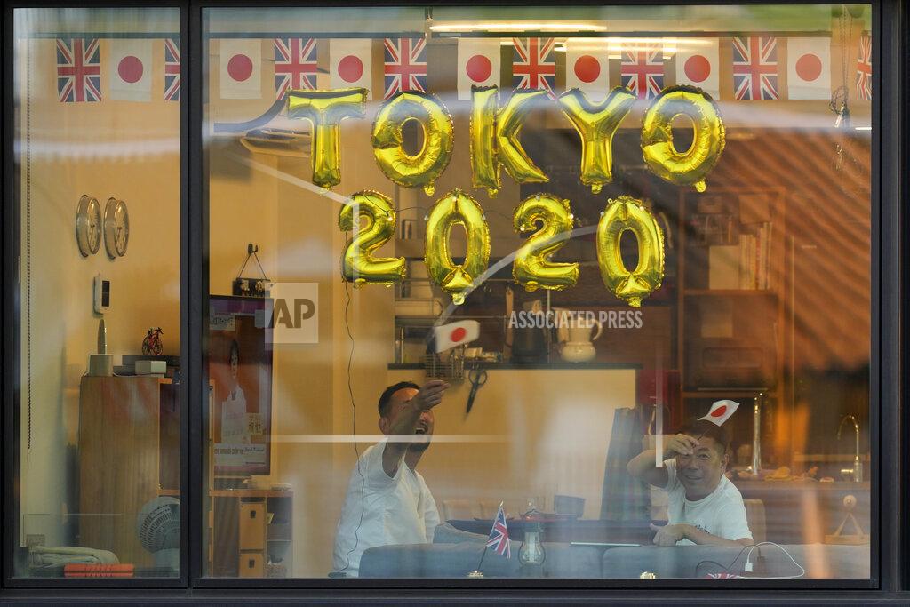 FILE - In this July 23, 2021, file photo, people look out their apartment window from a nearby building before the opening ceremony in the Olympic Stadium at the 2020 Summer Olympics in Tokyo, Japan. (AP Photo/Lee Jin-man, File)