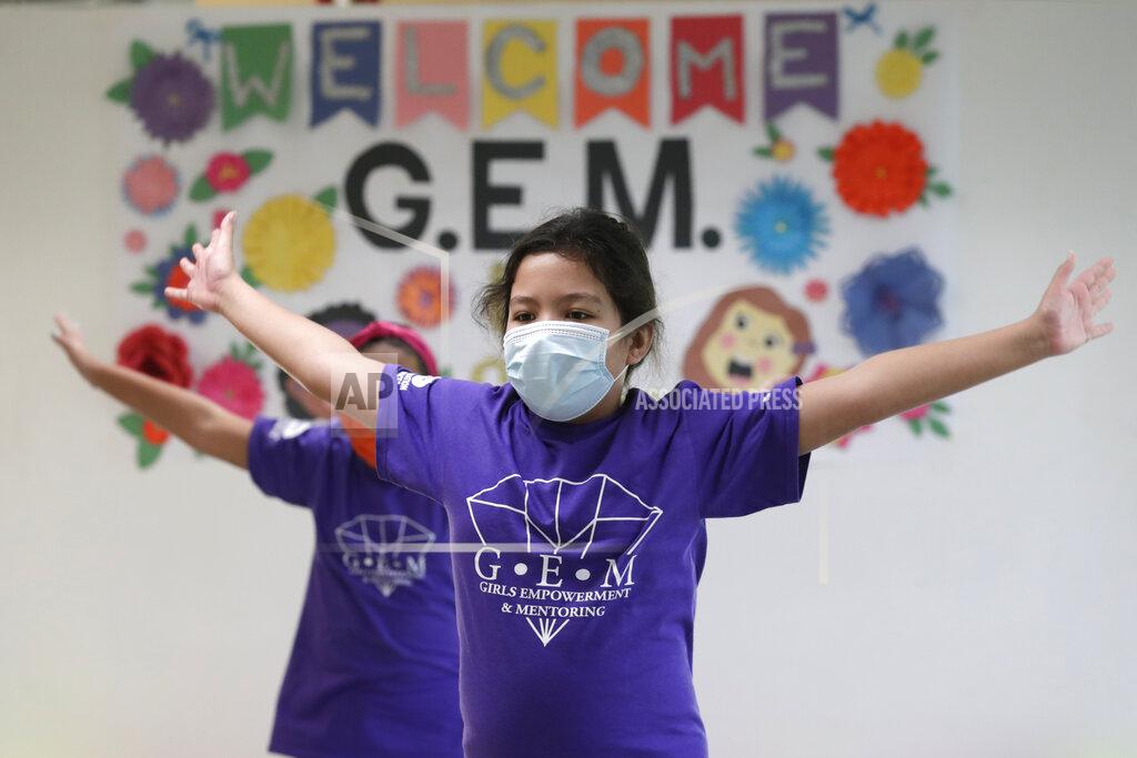 Maria Esposito stretches during a dance class at the Girl's Empowerment and Mentoring (G.E.M.) Summer Arts Camp during the coronavirus pandemic, Wednesday, July 15, 2020, in Miami. This Miami-Dade County summer camp program is operating at limited capacity, and has enhanced health screening and sanitizing procedures, practices social distancing, and required wearing of face coverings. (AP Photo/Lynne Sladky)