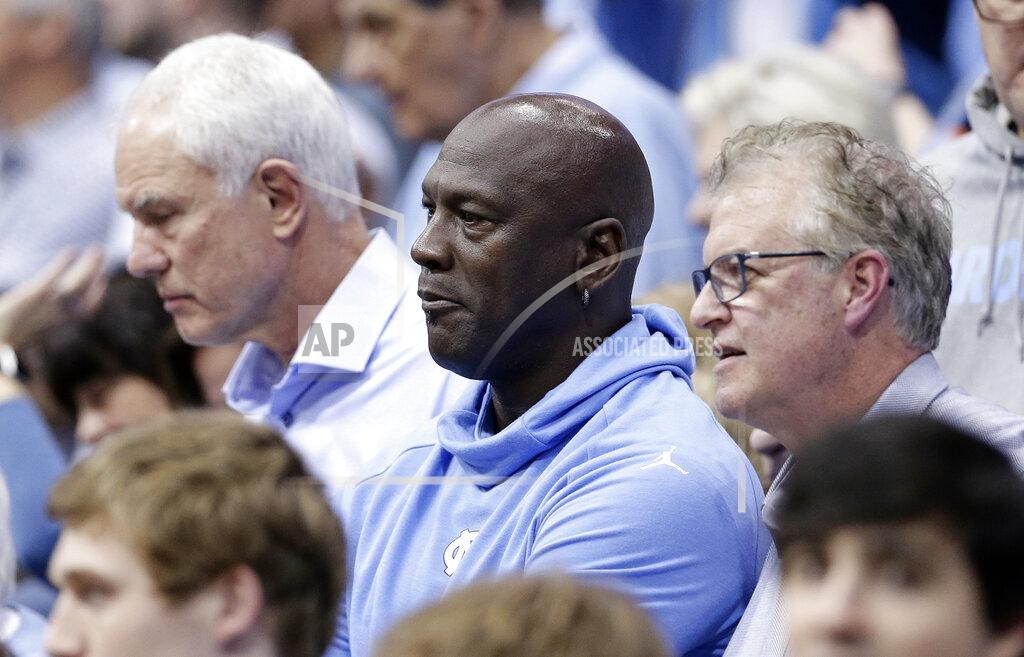 Gerry Broome Charlotte Hornets owner and former North Carolina great Michael Jordan, center, watches North Carolina play Virginia during an NCAA college basketball game in Chapel Hill, N.C., Monday, Feb. 11, 2019. At right is former North Carolina player Buzz Peterson, assistant general manager of the Hornets, and at left is former North Carolina player Mitch Kupchak, general manager of the Hornets. Peterson knew Jordan as well as anyone when they were in college. Roommates and teammates at North Carolina, they spent countless days competing on the basketball court in practice and endless hours talking hoops. But Peterson never saw this coming: His roommate becoming an NBA owner and hosting the league’s All-Star game in his home state of North Carolina. (AP Photo/Gerry Broome)