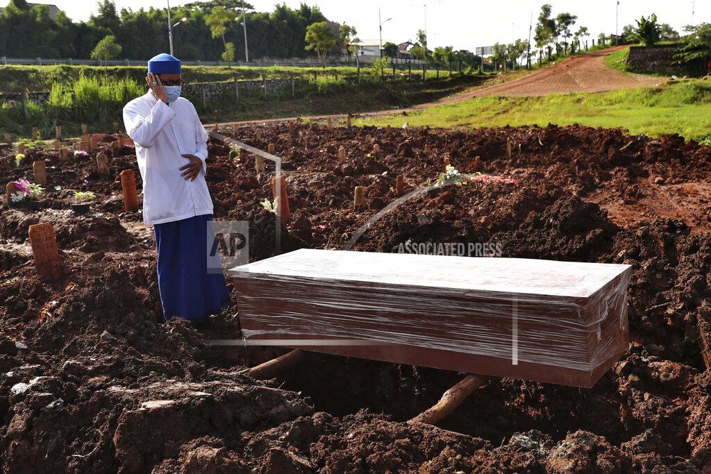 Tatan Syuflana An Islamic cleric recites the call of prayer during the burial of a man at the special section of Jombang Public Cemetery reserved for those who died of COVID-19, in Tangerang on the outskirts of Jakarta, Indonesia,Monday, June 21, 2021. Indonesia saw significant spikes in confirmed COVID-19 cases recently, an increase blamed on travel during last month's Eid al-Fitr holiday as well as the arrival of new virus variants, such as the the Delta version first found in India. (AP Photo/Tatan Syuflana)