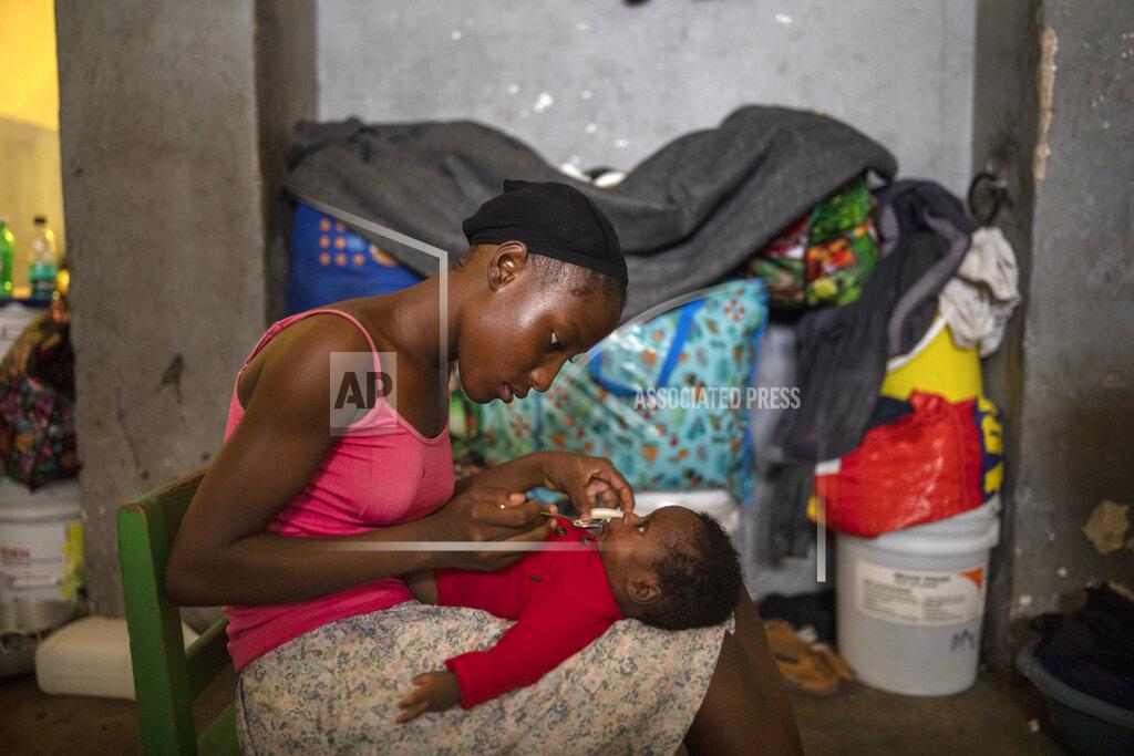 Rodrigo Abd A woman feeds her infant son in a shelter for internally displaced people due to violence, at a school converted into a shelter, in Port-au-Prince, Haiti, Tuesday, Sept. 14, 2021. Officials say the gangs' fight over territory in Port-au-Prince has forced hundreds of families to abandon burned or ransacked homes in impoverished communities, with many of them staying in gymnasiums and other temporary shelters that are running out of water, food and items like blankets and clothes. (AP Photo/Rodrigo Abd)