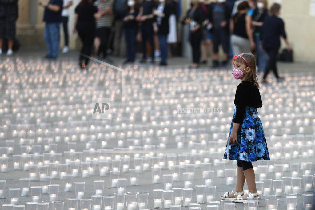 Petr David Josek A young girl walks to light up candles to commemorate victims of the COVD-19 pandemic at the Prague Castle in Prague, Czech Republic, Monday, May 10, 2021. The Czech Republic is massively relaxing its coronavirus restrictions as the hard-hit nation pays respect to nearly 30,000 dead. (AP Photo/Petr David Josek)