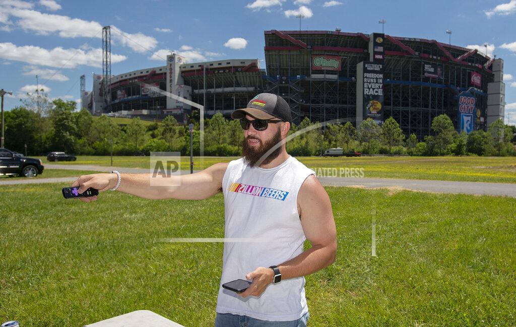 Andre Teague Cody Underwood of Knoxville, Tennessee uses a remote to fix the signal on a large TV set up so he and his friends could watch the live NASCAR race Sunday afternoon at Bristol Motor Speedway. (Andre Teague/Bristol Herald Courier via AP)