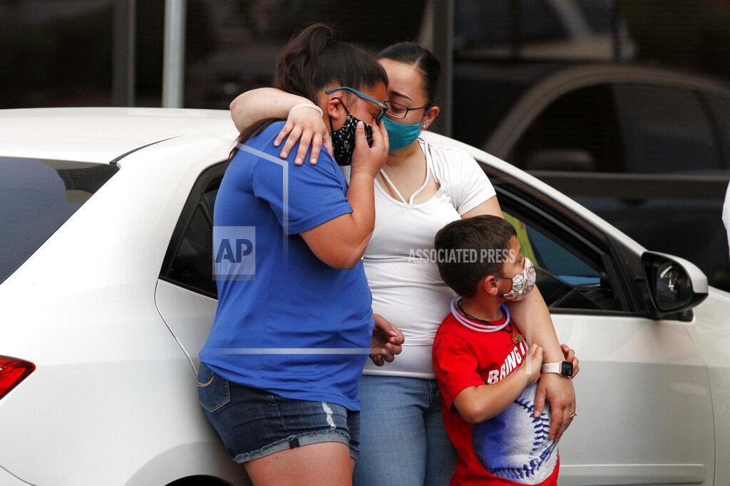 Cedar Attanasio In this Thursday, May 21, 2020 photo, widow Jessica Coco Garcia, hugs her children at a memorial in the Del Sol Medical Center parking lot for father Guillermo "Memo" Garcia in El Paso, Texas. Memo Garcia died from bullet wounds he suffered in the Aug. 3 shooting at a Walmart after nine months in the hospital. Mourners wore masked and tried to stay apart to prevent the spread of COVID-19. (AP Photo/Cedar Attanasio)