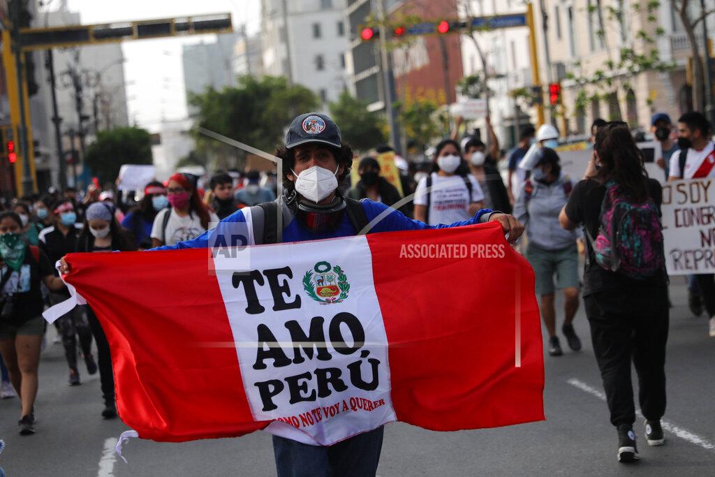 Rodrigo Abd A supporter of ousted President Martin Vizcarra holds a banner with a message that reads in Spanish, "I love you Peru, how could I not," as people refusing to recognize the new government march in downtown Lima, Peru, Wednesday, Nov. 11, 2020. On Tuesday, Peru swore in Manuel Merino as president, after Peru’s legislature booted Vizcarra from office on Monday. (AP Photo/Rodrigo Abd)