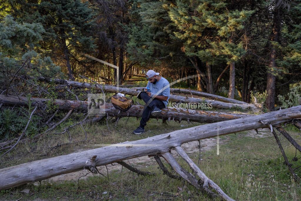 Dar Yasin Faheem Abdullah, a Kashmiri writer and singer composes a song sitting on a fallen tree inside an island on the outskirts of Srinagar, Indian controlled Kashmir, June 14, 2022. Musicians and artists in Kashmir are ordinary in life, each clutching onto the lived experiences of growing up in one of the world's most militarized zones that has known little but conflict for decades. But together, they embody a new form of music, a blend of progressive rock and hip hop that is an assertive expression of the region's political and cultural aspirations. (AP Photo/Dar Yasin)