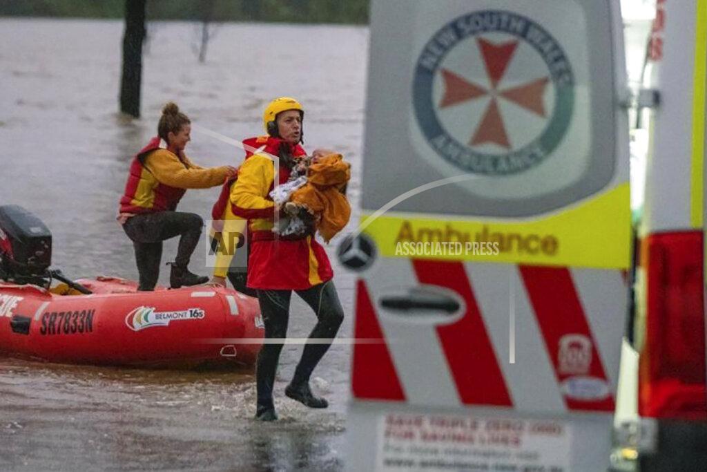 Uncredited In this photo provided by the State Emergency Service, surf lifesaver Lee Archer carries a baby as the child and the mother are rescued from flood waters in Bulga, Australia, Wednesday, July, 6, 2022. Floodwaters were receding in Sydney and its surrounds on Thursday, July 7, 2022, as heavy rain continued to threaten to inundate towns north of Australia's largest city. (State Emergency Service via AP)
