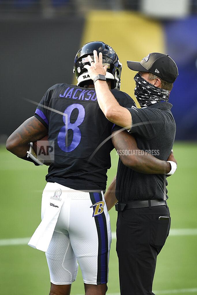 Gail Burton FILE - Baltimore Ravens quarterback Lamar Jackson, left, hugs head coach John Harbaugh during an NFL football training camp practice, Saturday, Aug. 29, 2020, in Baltimore, Md. They'll be playing Sunday in an empty stadium, facing a Cleveland Browns team with a new coaching staff that’s provided no clue how they plan to employ a revamped offense. “A lot of unknowns," Ravens coach John Harbaugh acknowledged. About the only thing for sure is that Baltimore quarterback Lamar Jackson, the multi-faceted reigning NFL MVP, will be the focal point of an offense that last year set a league record with 3,296 yards rushing and helped the Ravens win the AFC North with the best regular-season record in the NFL. (AP Photo/Gail Burton, FIle)