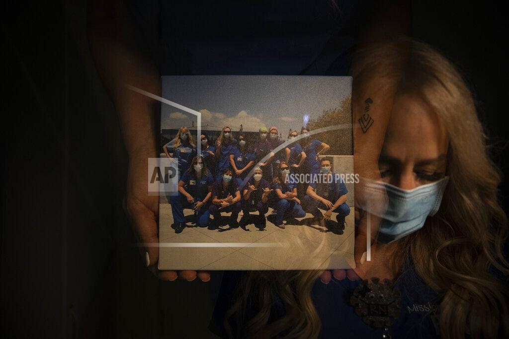 In this photo created with an in-camera multiple exposure, registered nurse Debbie Wooters, part of a group of nurses who had been treating coronavirus patients in an intensive care unit, holds a group picture taken with her fellow nurses in the empty COVID-19 ICU at Providence Mission Hospital in Mission Viejo, Calif., Tuesday, April 6, 2021. Many patients were frightened when told they would be put on a ventilator. Wooters remembers a patient who "looked at me and said, through his gasping breath, 'I don't want to die.'" (AP Photo/Jae C. Hong)