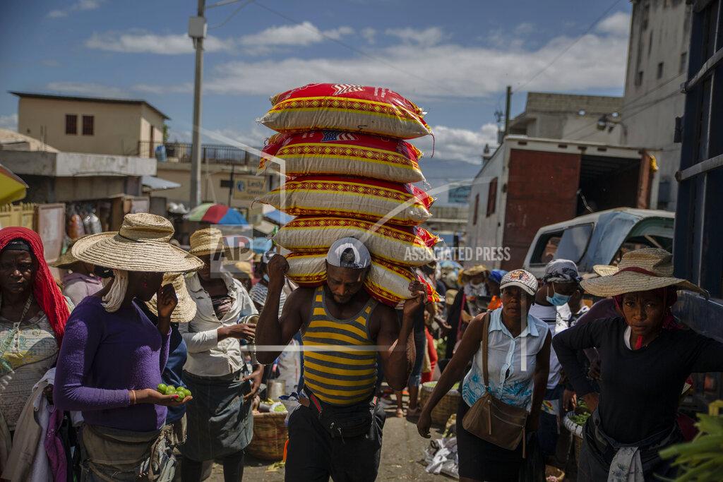 Joseph Odelyn A man carries goods at a street market in Port-au-Prince, Haiti, Saturday, June 5, 2021. Haiti defied predictions and perplexed health officials by avoiding a COVID-19 crisis for more than a year, but the country of more than 11 million people that has not received a single vaccine is now battling a spike in cases and deaths. (AP Photo/Joseph Odelyn)