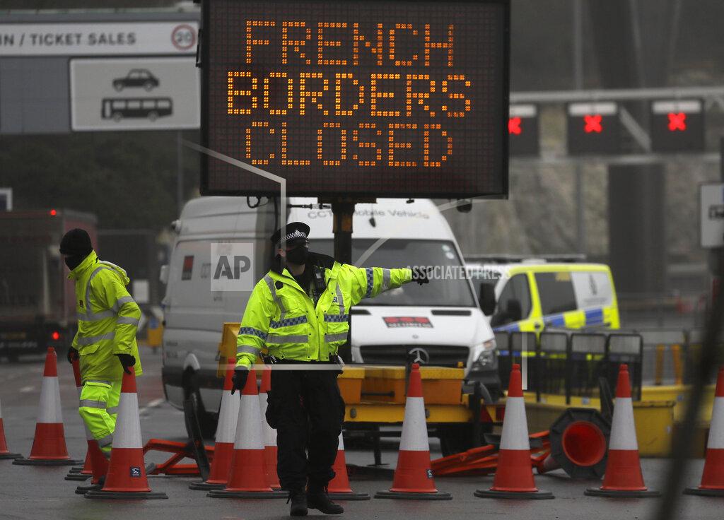 Kirsty Wigglesworth A police officer directs traffic at the entrance to the closed ferry terminal in Dover, England, Monday, Dec. 21, 2020, after the Port of Dover was closed and access to the Eurotunnel terminal suspended following the French government's announcement. France banned all travel from the UK for 48 hours from midnight Sunday, including trucks carrying freight through the tunnel under the English Channel or from the port of Dover on England's south coast. (AP Photo/Kirsty Wigglesworth)