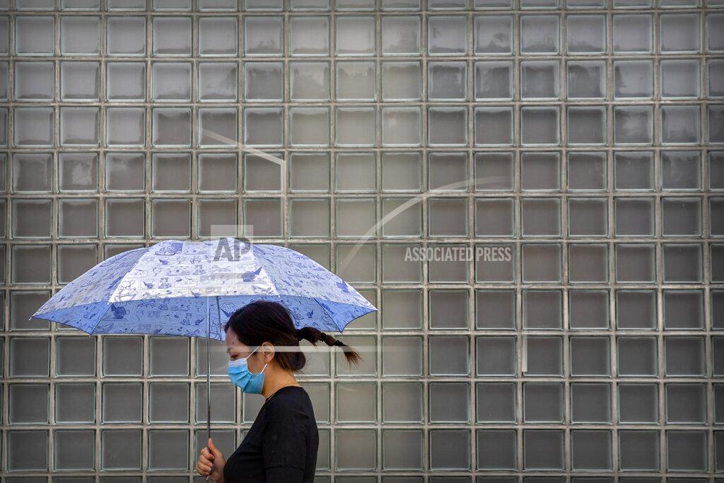 Mark Schiefelbein A woman wearing a face mask to protect against the coronavirus walks past a shopping mall on a rainy day in Beijing, Wednesday, Sept. 23, 2020. Even as China has largely controlled the outbreak, the coronavirus is still surging across other parts of the world. (AP Photo/Mark Schiefelbein)