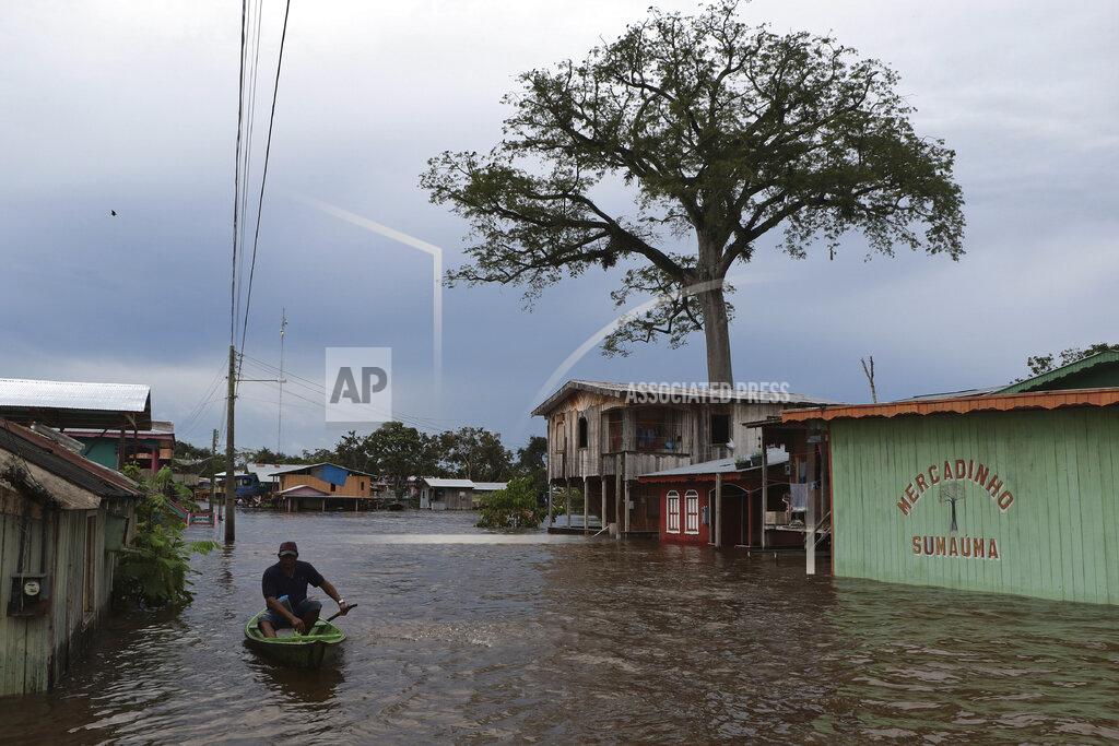 Edmar Barros A resident navigates a flooded street in Anama, Amazonas state, Brazil, Thursday, May 13, 2021. (AP Photo/Edmar Barros)