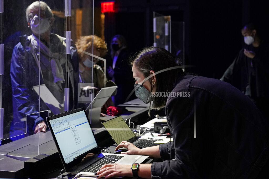 Kathy Willens Concertgoers are protected behind plastic protectors as an employee checks her computer for their reservations before the start of a performance by the New York Philharmonic at The Shed in Hudson Yards, Wednesday, April 14, 2021, in New York. It was the first time the Philharmonic had performed together for a live audience since March 10, 2020. (AP Photo/Kathy Willens)