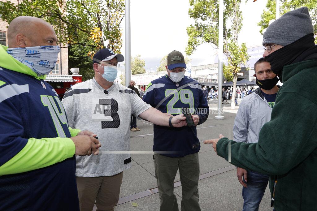 John Froschauer FILE - In this Sept. 19, 2021, file photo, stadium worker, right, checks for proof of vaccine against COVID-19 as fans prepare to enter Lumen Field before an NFL football game between the Seattle Seahawks and the Tennessee Titans in Seattle. Ticket agents dutifully ascertain the vaccination status of everyone passing through the turnstile at pro sports venues in some cities from Seattle and New York, and restaurant hosts do the same in many places. (AP Photo/John Froschauer, File)