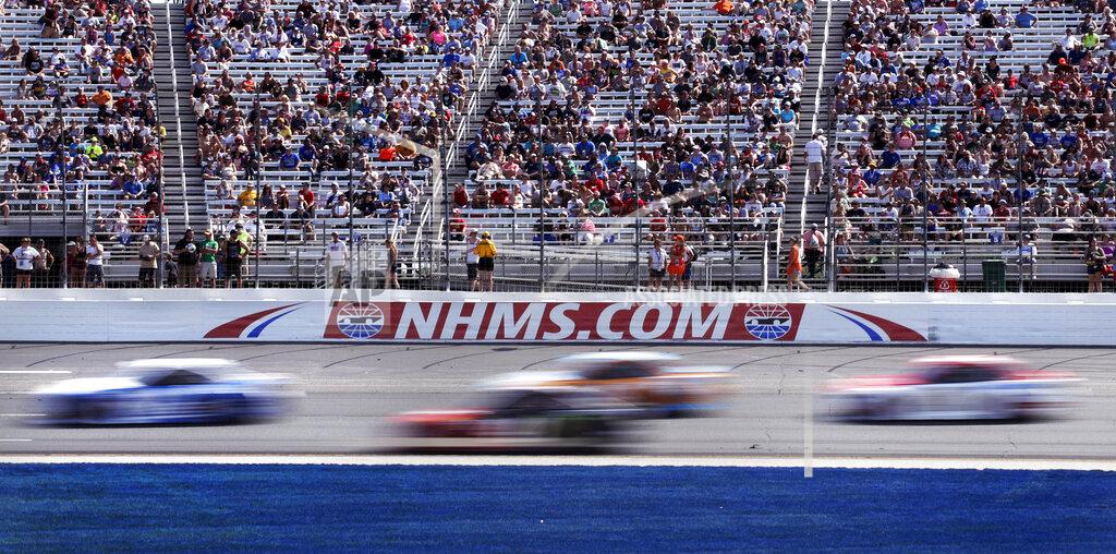 FILE - In this July 16, 2017, file photo, cars steer through Turn 1 as fans watch from nearly half-full stands during the NASCAR Cup Series 301 auto race at New Hampshire Motor Speedway in Loudon, N.H. New Hampshire Motor Speedway will allow fans in the grandstands and suites for the Aug. 2 NASCAR Cup Series race. Fans will be subject to social distancing requirements and additional health and safety protocols. (AP Photo/Charles Krupa, File)