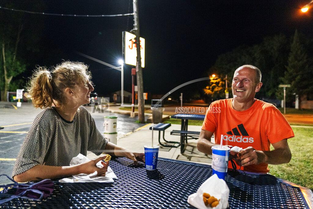 David Goldman Scott Rice, right, laughs with his daughter, Cassidy, 20, over burgers at JD's on her last night before she returns to college, Aug. 20, 2020, in Appleton, Wis. Rice concedes that the economy is not just an argument for President Donald Trump, it's also an argument against him. His daughter tells him so. She is studying public health at George Washington University and will cast her first presidential vote for Biden. "The fact that there was a pandemic and the fact that it had those consequences on the economy should be an eye opener, like, hey, maybe we're not doing this correctly," she said. (AP Photo/David Goldman)