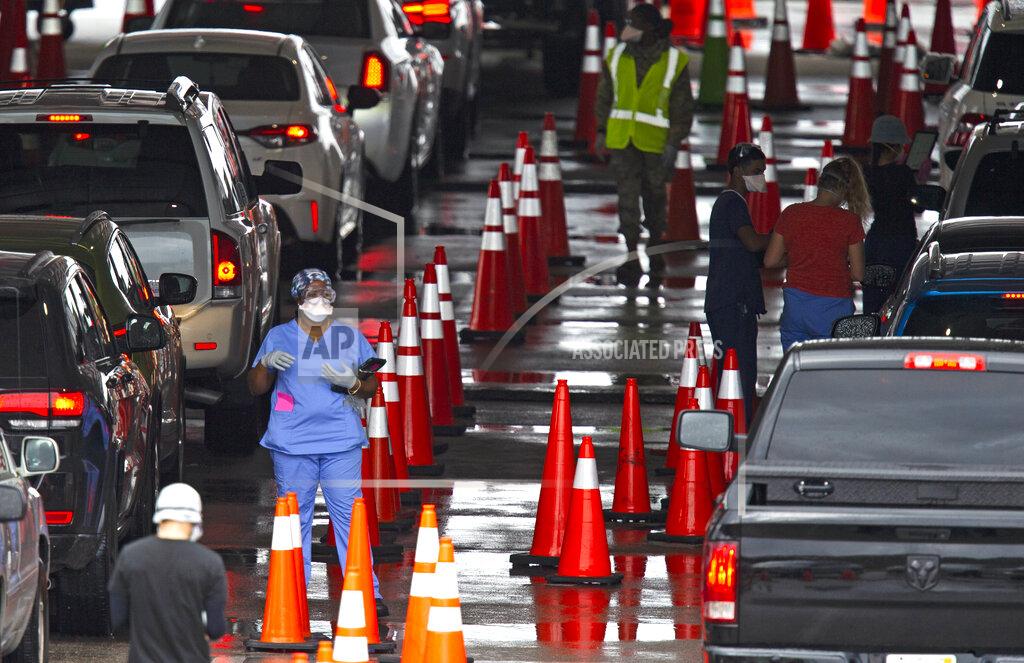 Vehicles line up as healthcare workers help to check-in as citizens are being tested at the COVID-19 drive-thru testing center at Hard Rock Stadium in Miami Gardens on Sunday, Nov. 22, 2020. (David Santiago/Miami Herald via AP)