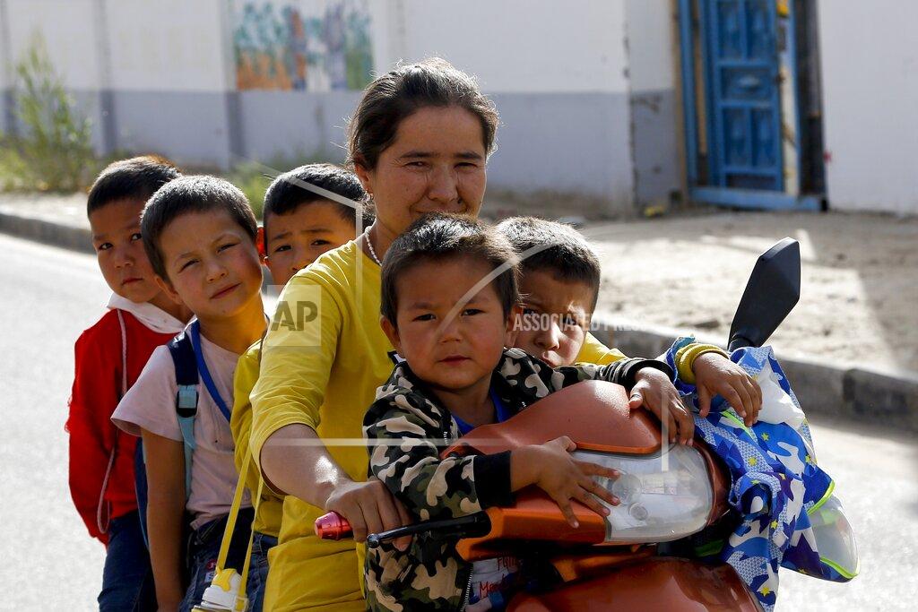 Andy Wong FILE - In this Sept. 20, 2018 file photo, a Uighur woman and children sit on a motor-tricycle after school at the Unity New Village in Hotan, in western China's Xinjiang region. Birth rates in the mostly Uighur regions of Hotan and Kashgar have plunged by more than 60% since 2015, government statistics show. (AP Photo/Andy Wong)