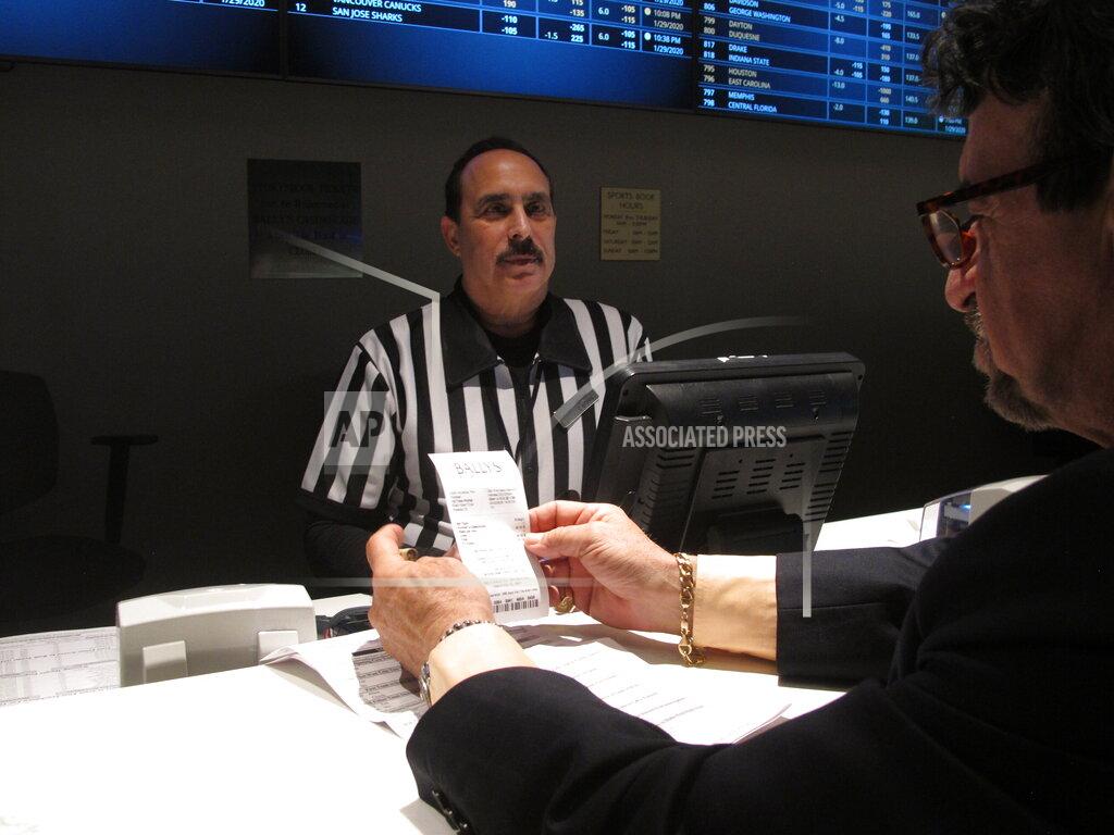 Wayne Parry In this Jan. 29, 2020 photo, a gambler checks his ticket after making a bet on the upcoming Super Bowl at Bally's casino in Atlantic City, N.J. Gambling industry officials expect Sunday's Super Bowl to be among the most heavily wagered-on championship games ever. (AP Photo/Wayne Parry)