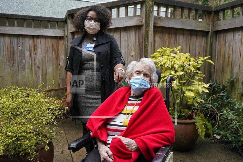 Ted S. Warren Sangu Kande, left, a nurse at Queen Anne Healthcare, a skilled nursing and rehabilitation facility in Seattle, poses for a photo, Friday, March 5, 2021, with Jean Allen, 96, one of the patients Kande cared for during the past year. Allen was infected and recovered from coronavirus. But 19 of her fellow residents and two beloved staff members died. The deaths trailed off, but the isolation and boredom continue. (AP Photo/Ted S. Warren)