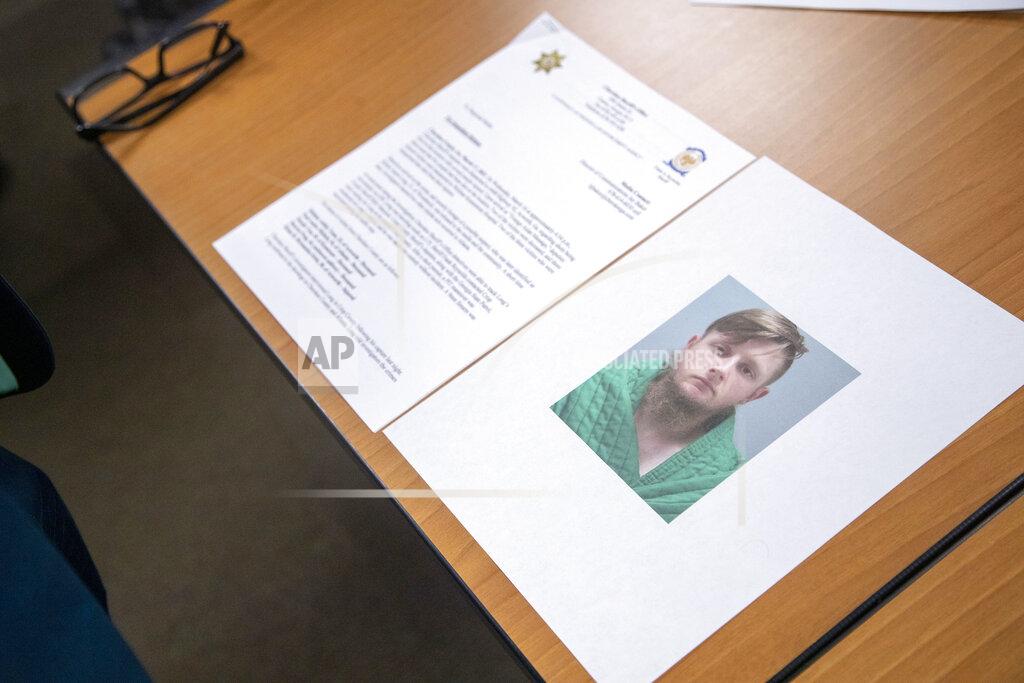 Alyssa Pointer An image of Robert Aaron Long is displayed near a press release provided by the Cherokee County Sheriff's Office during a press conference at the Atlanta Police Department headquarters in Atlanta, Wednesday, March 17, 2021. Long is accused of killing multiple people, most of whom were of Asian descent, at massage parlors in the Atlanta area. (Alyssa Pointer/Atlanta Journal-Constitution via AP)