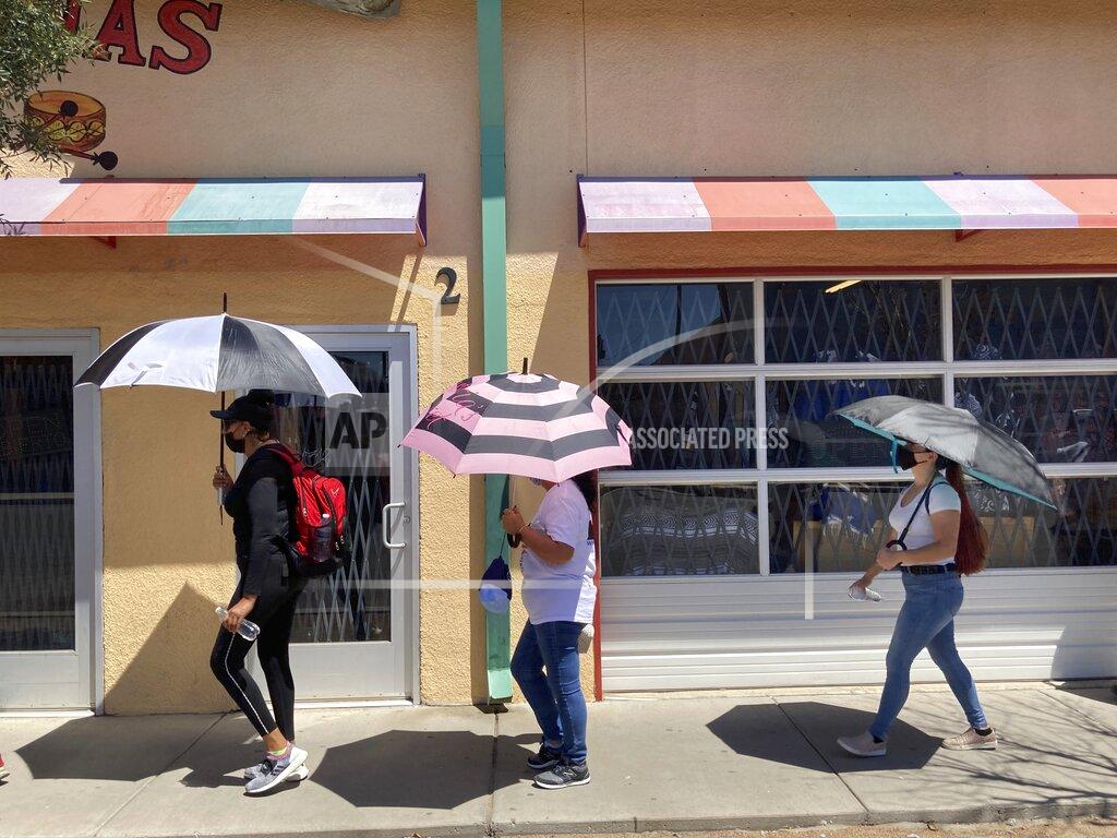 Morgan Lee Daisy Arvizu, right, participates in a street march in support of immigrant rights on Aug. 26, 2021, in El Paso, Texas, amid lingering concerns about gun violence targeting immigrants. She was at work inside a Walmart in El Paso in August 2019 when a gunman opened fire in a shooting that killed 23 people, spurring her husband, Martin Portillo, to later to buy a handgun for their protection. A new "constitutional carry" law in Texas allows most gun owners age 21 and older to carry a holstered handgun — concealed or not — in public without getting a license and related training. (AP Photo/Morgan Lee)