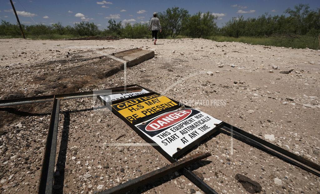 Eric Gay Ashley Williams Watt walks across the site of an abandoned well at her ranch, Friday, July 9, 2021, near Crane, Texas. Some of her wells are leaking chemicals such as benzene, a known carcinogen, into fields and drinking water. (AP Photo/Eric Gay)