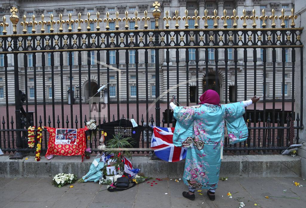 Tony Hicks A woman gestures as she sings next to tributes left in honor of Britain's Prince Philip in front of Buckingham Palace in London on Saturday, April 10, 2021. Prince Philip, the irascible and tough-minded husband of Queen Elizabeth II who spent more than seven decades supporting his wife in a role that both defined and constricted his life, has died, Buckingham Palace said Friday. He was 99. (AP Photo/Tony Hicks)
