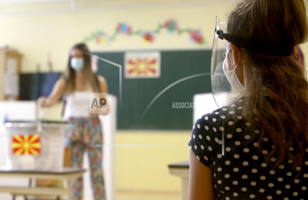 Boris Grdanoski A member of the electoral committee wearing a face shield and a mask, observes the voting process in a polling station in Skopje, North Macedonia on Wednesday, July 15, 2020. Voters in North Macedonia headed to the polls early on Wednesday in the country's general election despite an alarming spike in coronavirus cases in the tiny Balkan nation. (AP Photo/Boris Grdanoski)