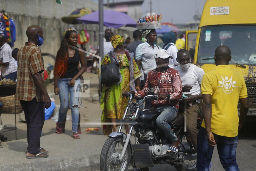Sunday Alamba People wait for transportation at a bus stop in Lagos, Nigeria, Thursday Dec. 31, 2020. A Nigerian scientist has spent the holiday season in his laboratory doing genetic sequencing to learn more about the country’s COVID-19 variant, as cases increase in the country. Virologist Sunday Omilabu says the information he gathers about the variant will help battle the spread of the disease in Nigeria, Africa’s most populous country with 196 million people. (AP Photo/Sunday Alamba)