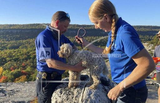In this photo provided by New York State Parks on Wednesday, Oct. 13, 2021, Ulster County SPCA Executive Director Gina Carbonari, right, and SPCA Supervisor Chris West, left, check a rescued a 12-year-old dog named Liza, found trapped after five days deep inside the narrow, rocky crevice at Minnewaska State Park Preserve in Kerhonkson, N.Y. A dog trapped for five days deep inside a narrow, rocky crevice at a state park north of New York City was rescued unharmed — though it was hungry and thirsty, parks officials said Wednesday. (New York State Parks via AP)