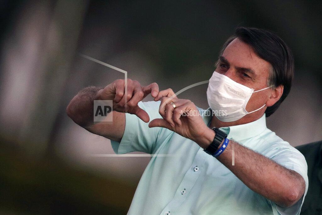 Eraldo Peres FILE - In this July 22, 2020, file photo, Brazil's President Jair Bolsonaro, who is infected with COVID-19, wears a protective face mask as he makes a heart-hand sign to supporters during a Brazilian flag retreat ceremony outside his official residence the Alvorada Palace, in Brasilia, Brazil. The Brazilian president announced his illness in July and used it to publicly extol hydroxychloroquine, the unproven malaria drug that he’d been promoting as a treatment for COVID-19 and was taking himself. (AP Photo/Eraldo Peres, File)