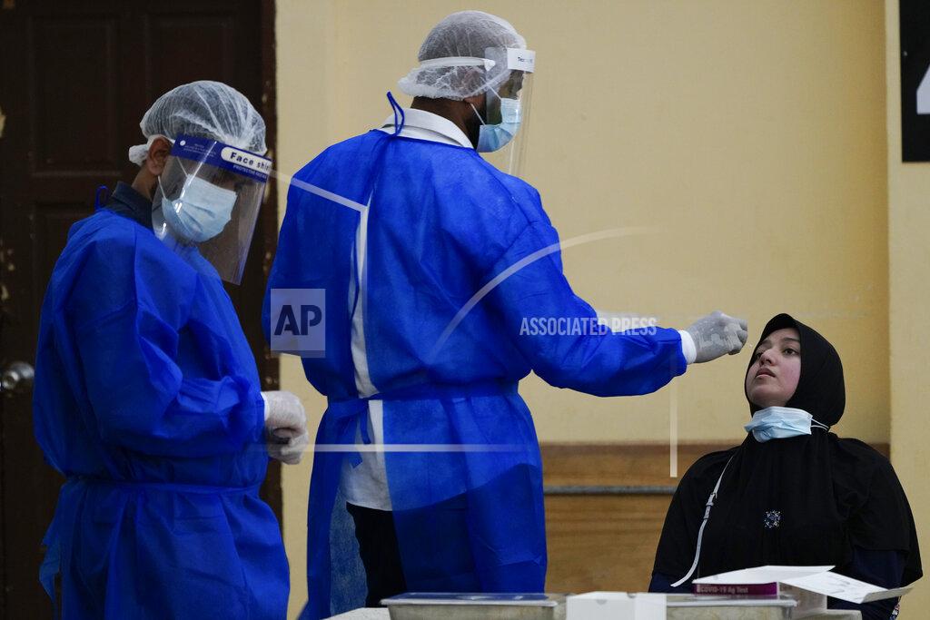 Vincent Thian A medical worker collects a swab sample from a woman during coronavirus testing in Petaling Jaya, Malaysia, Monday, Jan. 18, 2021. Malaysian authorities imposed tighter restrictions on movement to try to halt the spread of the coronavirus. (AP Photo/Vincent Thian)