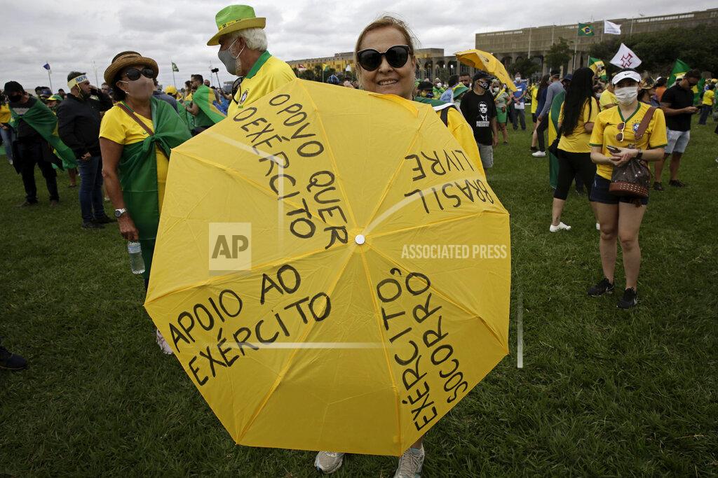 Eraldo Peres A woman holds an umbrella marked with pro-military phrases in Portuguese, during a rally backing President Jair Bolsonaro’s anti-coronavirus-lockdown stance, marking May Day, or International Workers' Day, in Brasilia, Brazil, Saturday, May 1, 2021. (AP Photo/Eraldo Peres)