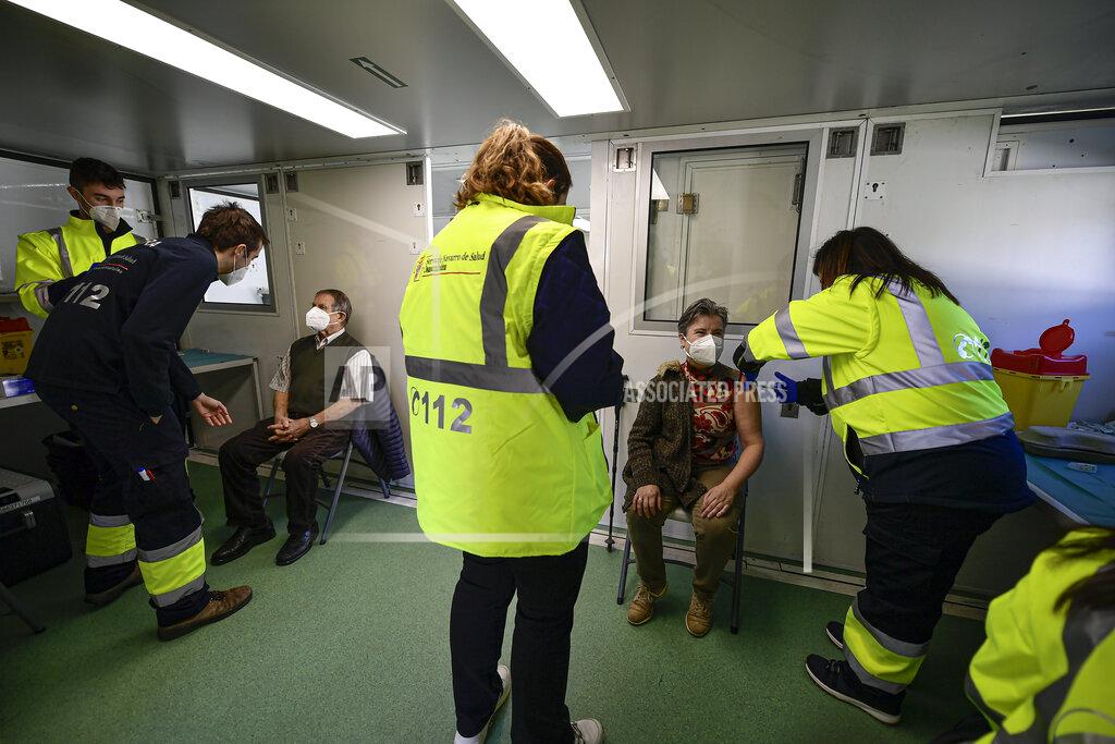 Alvaro Barrientos Lola Basaret, 57 and Julio Larrea, 88, are vaccinated with the Pfizer vaccine against coronavirus inside a mobile health unit in the small Pyrenees village of Oronoz-Mugaire, around 45 km (27 miles) from Pamplona, northern Spain, Tuesday, Jan. 19. 2021. (AP Photo/Alvaro Barrientos)