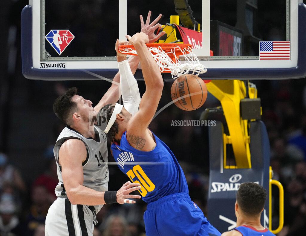 David Zalubowski Denver Nuggets forward Aaron Gordon, right, hangs from the rim after a dunk next to San Antonio Spurs forward Drew Eubanks during the first half of an NBA basketball game Friday, Oct. 22, 2021, in Denver. (AP Photo/David Zalubowski)