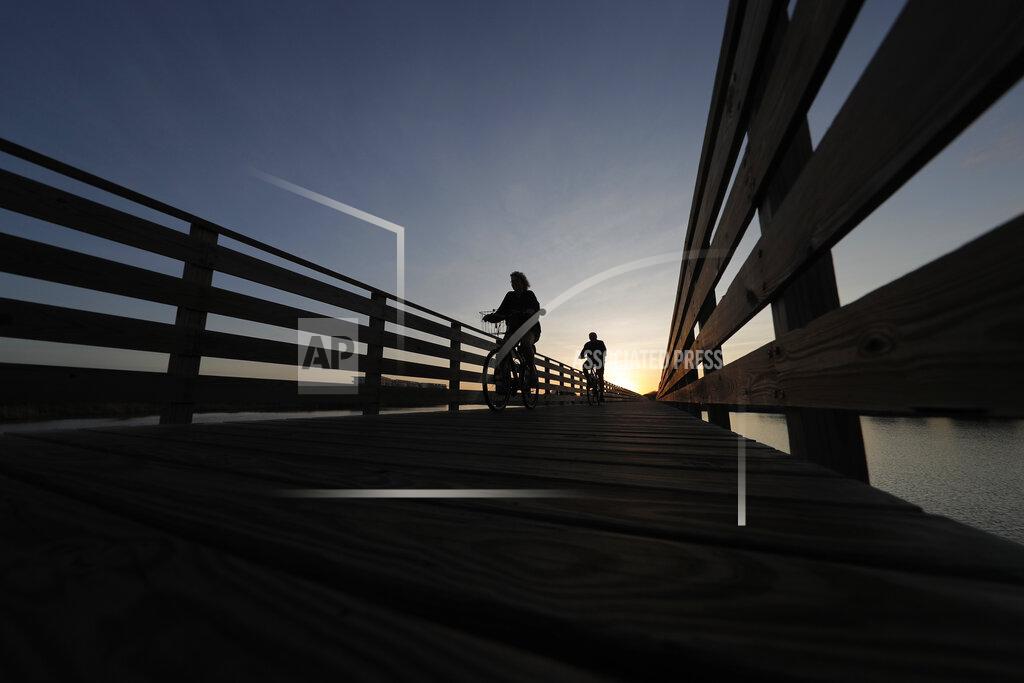 Gerald Herbert In this March 12, 2020, photo, People ride bikes on a nature boardwalk, that was funded with money from BP due to the Deepwater Horizon oil spill, in Gulf State Park in Gulf Shores, Ala. As oil spewed into the Gulf of Mexico from a blown-out BP well in 2010, residents wondered whether their home would ever be the same. A decade later, it’s not. The Deepwater Horizon disaster changed the region, with a flood of spending altering landscapes and attitudes. (AP Photo/Gerald Herbert)