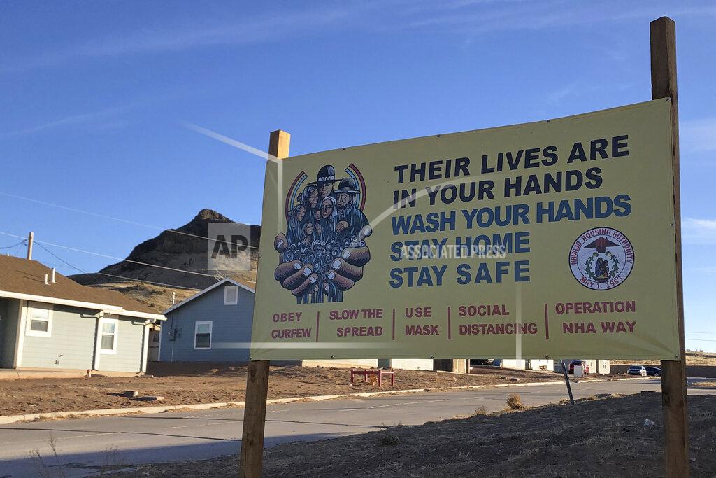 Felicia Fonseca A sign urging safety measures during the coronavirus pandemic is seen in Teesto, Arizona, on the Navajo Nation on Feb. 11, 2021. Teesto workers, health representatives, volunteers and neighbors keep close tabs on another to ensure the most vulnerable citizens get the help they need. (AP Photo/Felicia Fonseca)