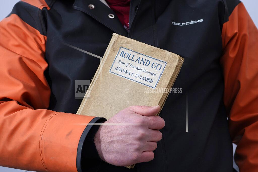 Bennett Konesni holds a book of sea shanties Thursday, Jan. 28, 2021, in Belfast, Maine. Work songs have helped sailors on long ocean journeys to break up the tedium. The genre is seeing a global revival among people bored and isolated by the coronavirus pandemic. (AP Photo/Robert F. Bukaty)